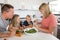 Young attractive couple mother and father preparing salad together with little son and young beautiful daughter in healthy vegetab