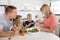 Young attractive couple mother and father preparing salad together with little son and young beautiful daughter in healthy vegetab