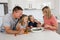 Young attractive couple mother and father preparing salad together with little son and young beautiful daughter in healthy vegetab