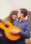 Young and attractive couple sitting near the couch with a guitar