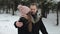 Young attractive couple walking and having fun in a winter forest under heavy snow. Man and woman in pink hat hugging