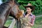 Young attractive cowgirl feeds horse in the farm