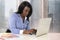 Young attractive and efficient black ethnicity woman sitting at business district office computer laptop desk typing