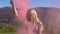 Young attractive emotional girl with color smoke dancing in the mountains