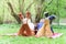 Young attractive european couple with small dog between them is getting rest on blanket in some summer park at warm sunny day.