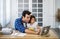 Young attractive father and little cute daughter watching the movie video on the tablet and eating potato chips at home