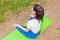 Young attractive female meditate in park.Young female relaxes in yoga pose in green summer nature