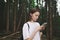 Young attractive female traveler using her smartphone maps application to find the way from mountain forest. Concentrated tourist