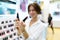 Young attractive girl consultant in a white shirt shows lipstick in a professional cosmetics salon