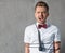 A young attractive glamorous man in a white shirt and a butterfly crocked in the microphone cord, on a gray background