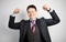 Young attractive guy businessman in suit on gray background with muscular arms, champion and superhero. Success in business