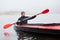 Young attractive guy having fun on kayak. Kayaking on river, attractive guy in boat sailing in river, holding oar in hands, looks