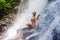 Young attractive and happy 30s woman with fit body practicing yoga wet under tropical paradise waterfall stream in meditation and