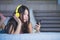 Young attractive and happy Asian Chinese woman with yellow headphones listening to music in mobile phone on bed at home smiling ha