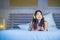Young attractive and happy Asian Chinese woman with yellow headphones listening to music in mobile phone on bed at home smiling ha
