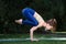 young attractive happy asian woman in yellow and blue outfit practicing her yoga balance, crane crow pose, at home outdoor garden