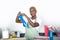 Young attractive and happy black african american woman cleaning home kitchen putting blue washing rubber gloves smiling cheerfu