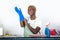 Young attractive and happy black african american woman cleaning home kitchen putting blue washing rubber gloves smiling cheerfu