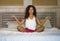 Young attractive and happy black afro American woman at home bedroom doing yoga meditation and body relaxation exercise stretching