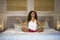 Young attractive and happy black hispanic woman at home bedroom doing yoga meditation and body relaxation exercise stretching on b