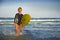 Young attractive and happy blonde surfer girl in beautiful beach carrying yellow surf board walking out of the sea enjoying summer