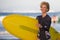 Young attractive and happy blonde surfer girl in beautiful beach carrying yellow surf board walking out of the water enjoying summ