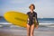 Young attractive and happy blonde surfer woman in beautiful beach carrying yellow surf board walking out of sea enjoying summer ho