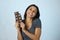 Young attractive and happy hispanic woman in blue top smiling excited eating chocolate bar background