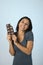 Young attractive and happy hispanic woman in blue top smiling excited eating chocolate bar background