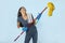 Young attractive happy Latin woman in washing gloves holding mop having fun singing and playing air guitar excited