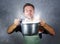 Young attractive happy and proud home cook man cooking soup holding kitchen pot smelling the meal aroma gesturing delighted and sa