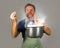 Young attractive happy and proud home cook man cooking soup holding kitchen pot smelling the meal aroma gesturing delighted and sa