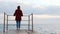 Young attractive happy woman standing on empty pontoon and looking at the horizon. Cute lonely female in jeans and red shirt stand