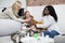 Young attractive high-skilled African lady doctor helping caring mother to put on her sick daughter& x27;s face nebulizer