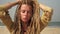 Young attractive hippie woman with dreadlocks on a hot day on the sandy beach