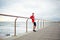 Young attractive jogger stands on the pier leaning on the rail