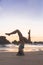 Young attractive latin woman wearing a bikini practicing yoga on the beach at sunset, healthy mental and body lifestyle concept