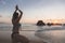 Young attractive latin woman wearing a bikini practicing yoga on the beach at sunset, healthy mental and body lifestyle concept