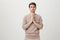 Young and attractive man with bristle standing with praying or begging gesture while expressing confidence and being