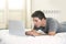 Young attractive man lying on bed or couch working on computer laptop typing connected to internet