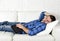 Young attractive man sleeping at home couch relaxing after working with digital tablet pad