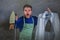 Young attractive messy and upset man in kitchen apron holding iron and burnt shirt with worried face expression in housework and d
