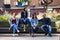 Young and attractive people are sitting on a bench in ghetto street.