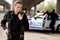 young attractive policewoman using walkie-talkie with blurred partner near car