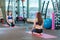 Young attractive pregnant woman in sportswear put hands on legs sitting on pink mat kneeling near bottle of water at gym