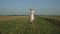 A young attractive rural woman walks through a field with mowed grass. Beautiful woman in a hat and boots, rustic