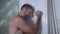 Young attractive sad and depressed man in the shower leaning against the wall thoughtful