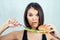 Young and attractive sad woman in black T-shirt and measuring tape is holding a calorie burger on a plate. concept of