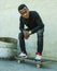 Young attractive and serious black afro American man squatting on skate board at grunge street corner looking cool posing in