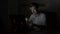 Young attractive student male video chatting and waving at web camera in a dark room at home -